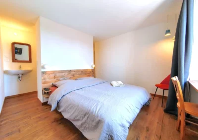 Chambre de Lorette à La Maison Folia avec lit double et chaise confortable