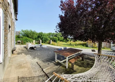 Terrasse extérieure de La Maison Folia avec hamac et coin détente en Normandie