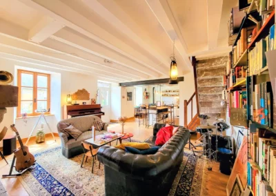 Grand salon de La Maison Folia avec canapé en cuir, bibliothèque, instruments de musique et coin détente
