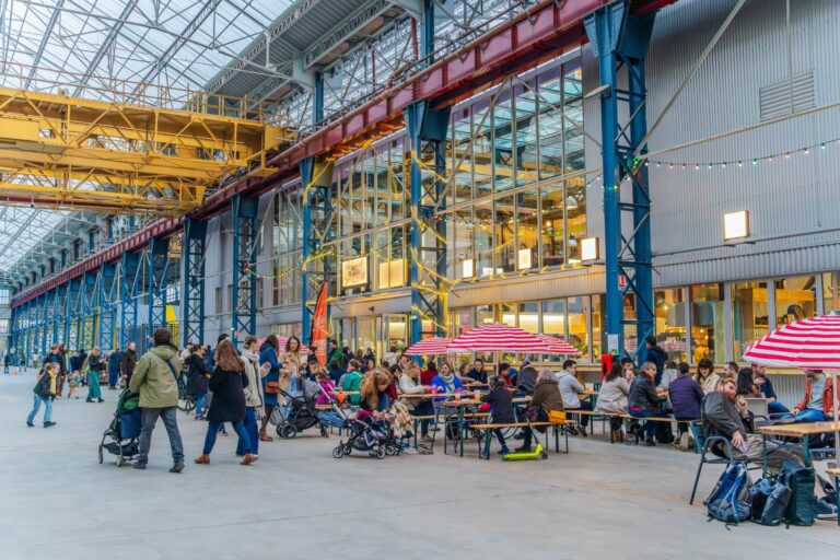 Tables et promeneurs sous les halles de Chaud Bouillon à Fives Cail